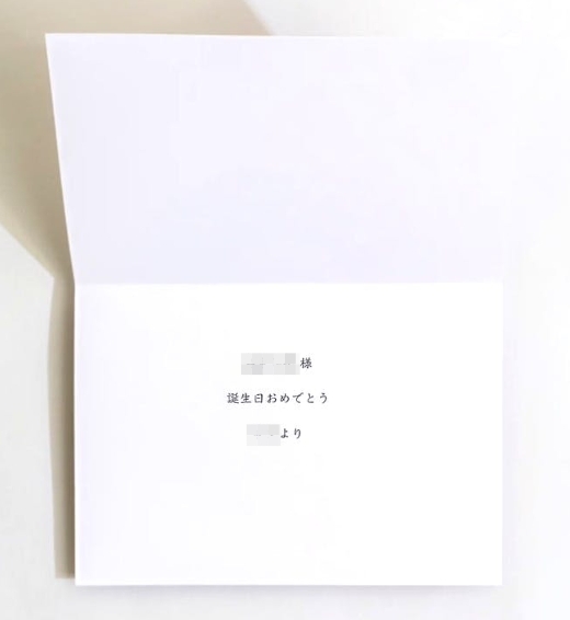 HitoHanaのメッセージカード印刷サンプル。白い二つ折りカードの中央に「○○様 誕生日おめでとう ○○より」というシンプルな文面が印字された実物写真。
